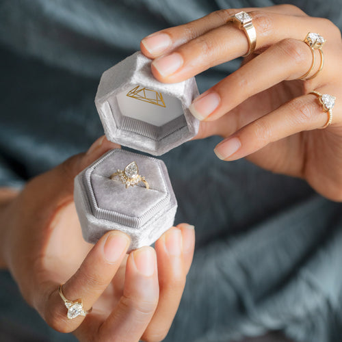 Model opening a purple velvet ring box with a lab grown white diamond engagement ring inside