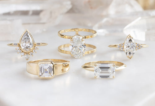 five lab grown white diamond engagement rings on white crystal