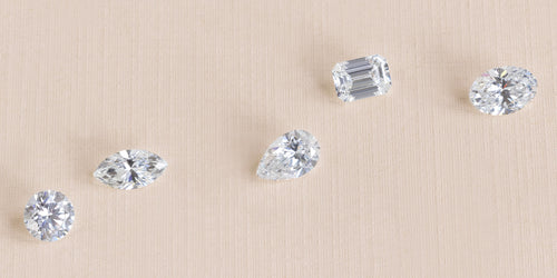 five loose lab grown diamonds on beige textured paper
