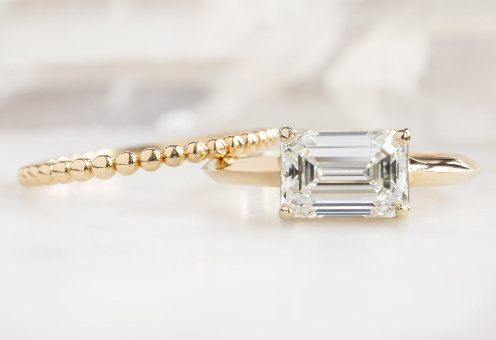 Beaded Stacking Band Leaning on The Bryn Ring with an Emerald-Cut Lab Grown Diamond 